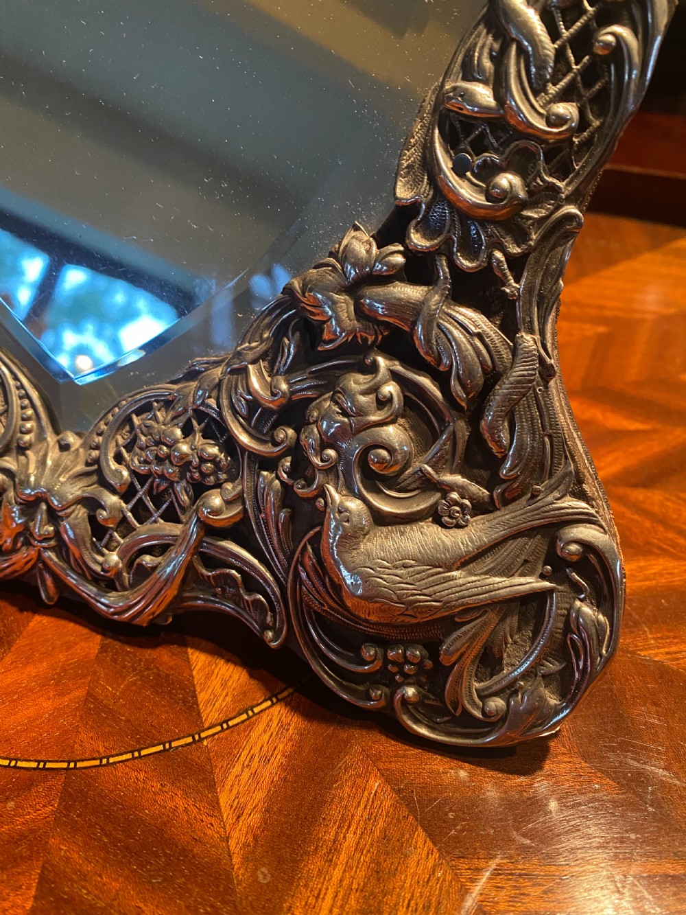 A heart-shaped silver easel mirror featuring intricate pierced scrollwork, floral motifs, bird details, and an engraved top cartouche. View II
