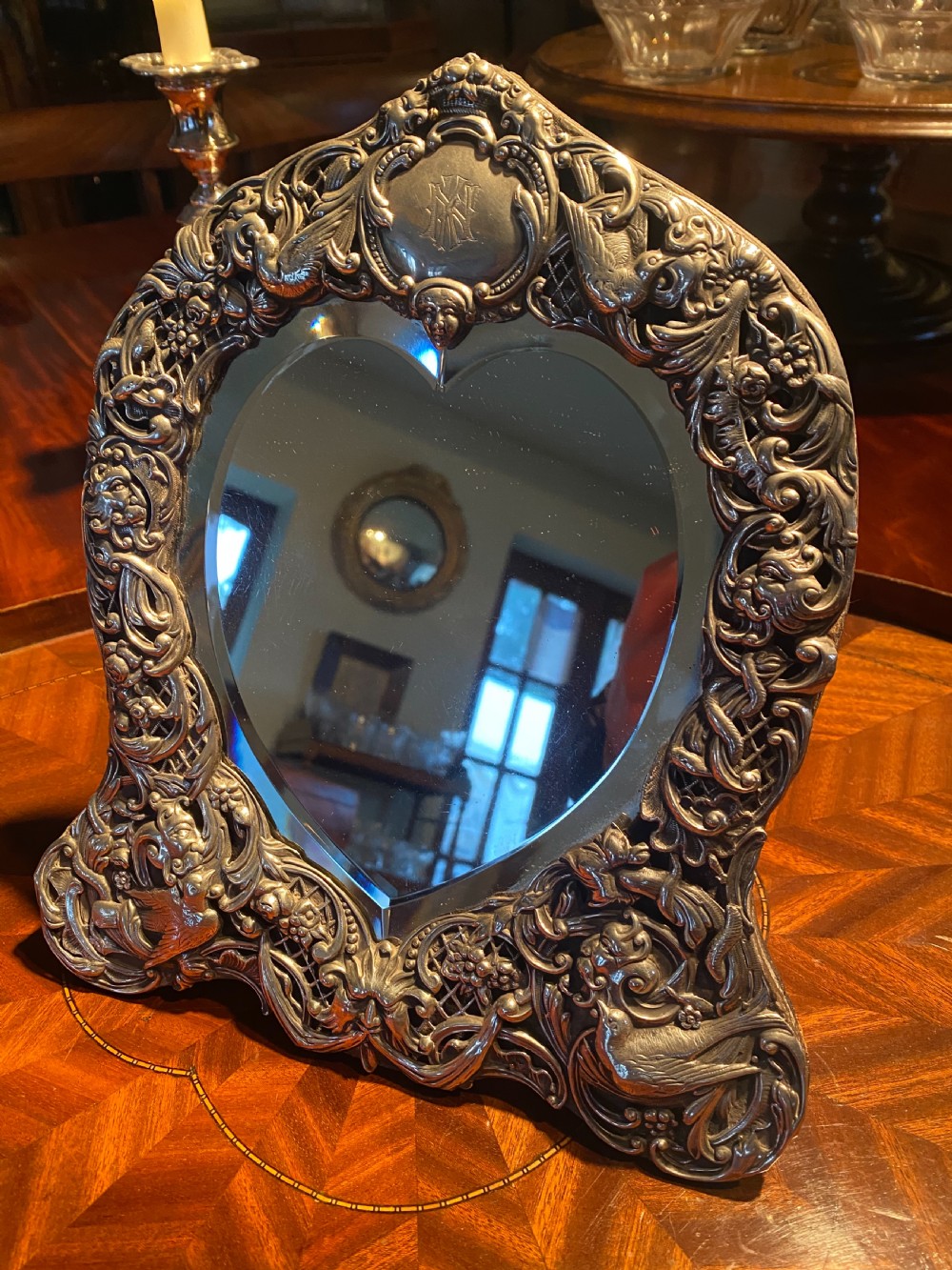 A heart-shaped silver easel mirror featuring intricate pierced scrollwork, floral motifs, bird details, and an engraved top cartouche. View III