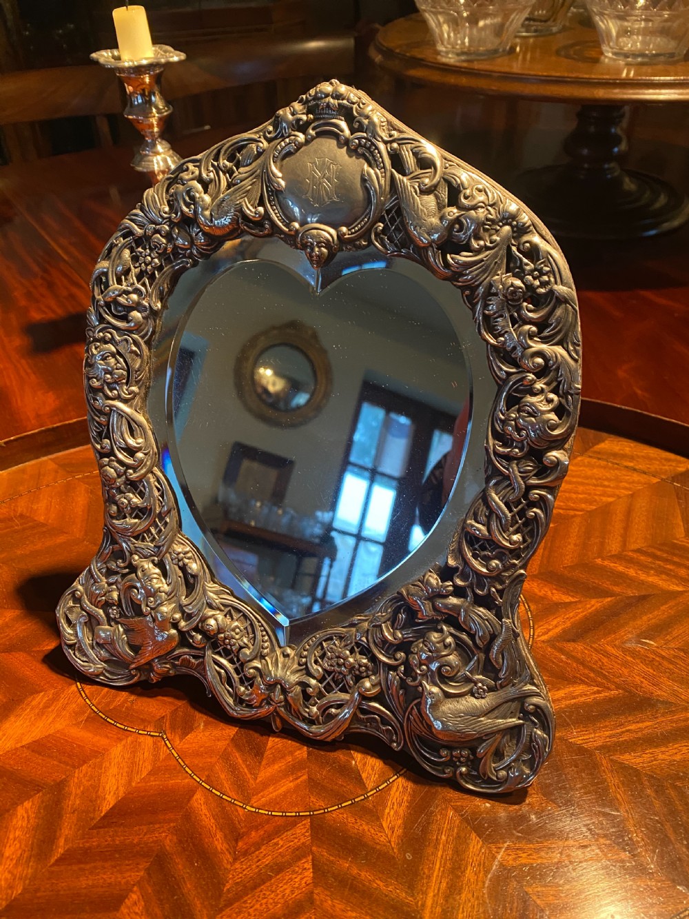 A heart-shaped silver easel mirror featuring intricate pierced scrollwork, floral motifs, bird details, and an engraved top cartouche. View IV