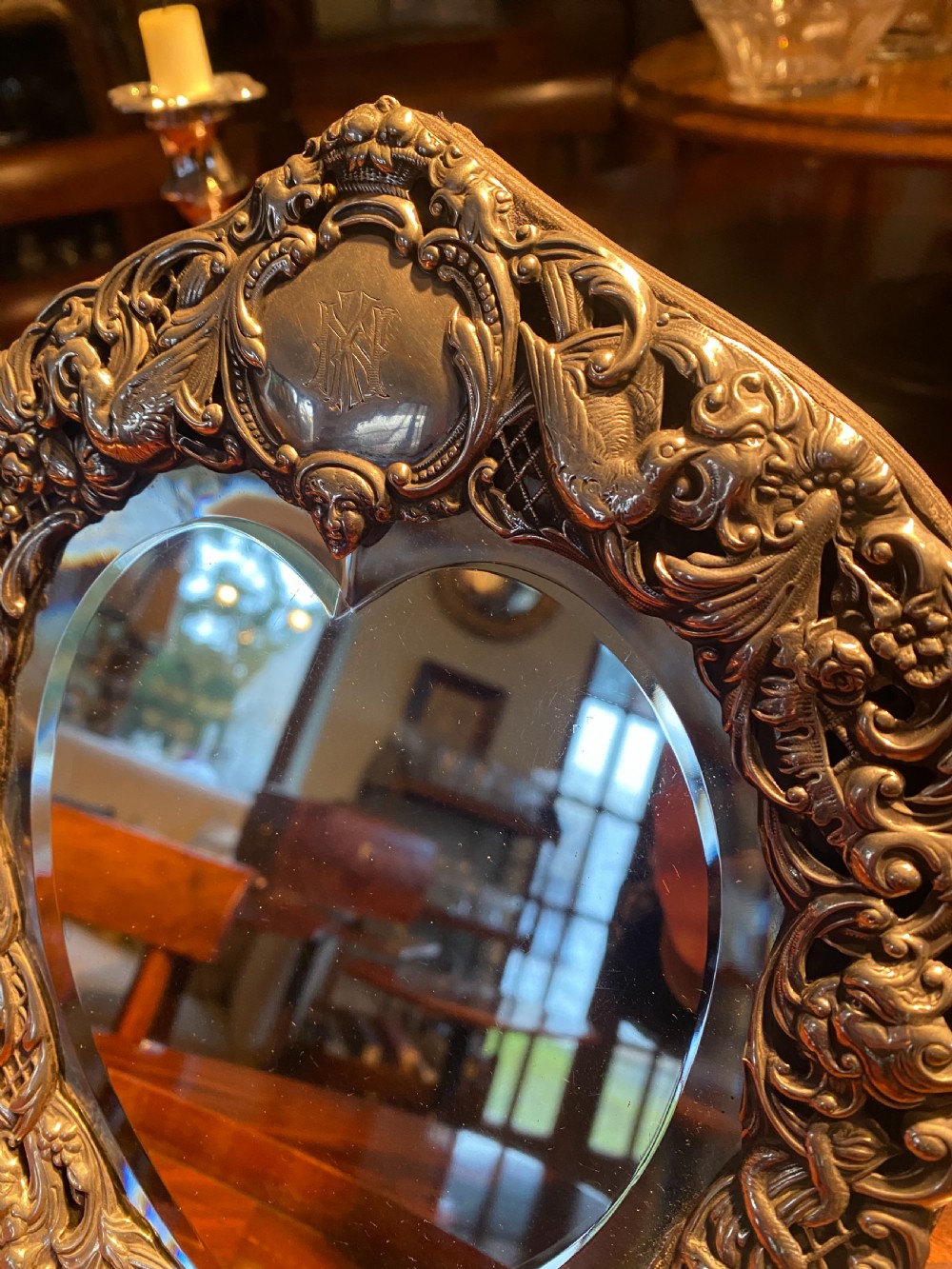 A heart-shaped silver easel mirror featuring intricate pierced scrollwork, floral motifs, bird details, and an engraved top cartouche. View V