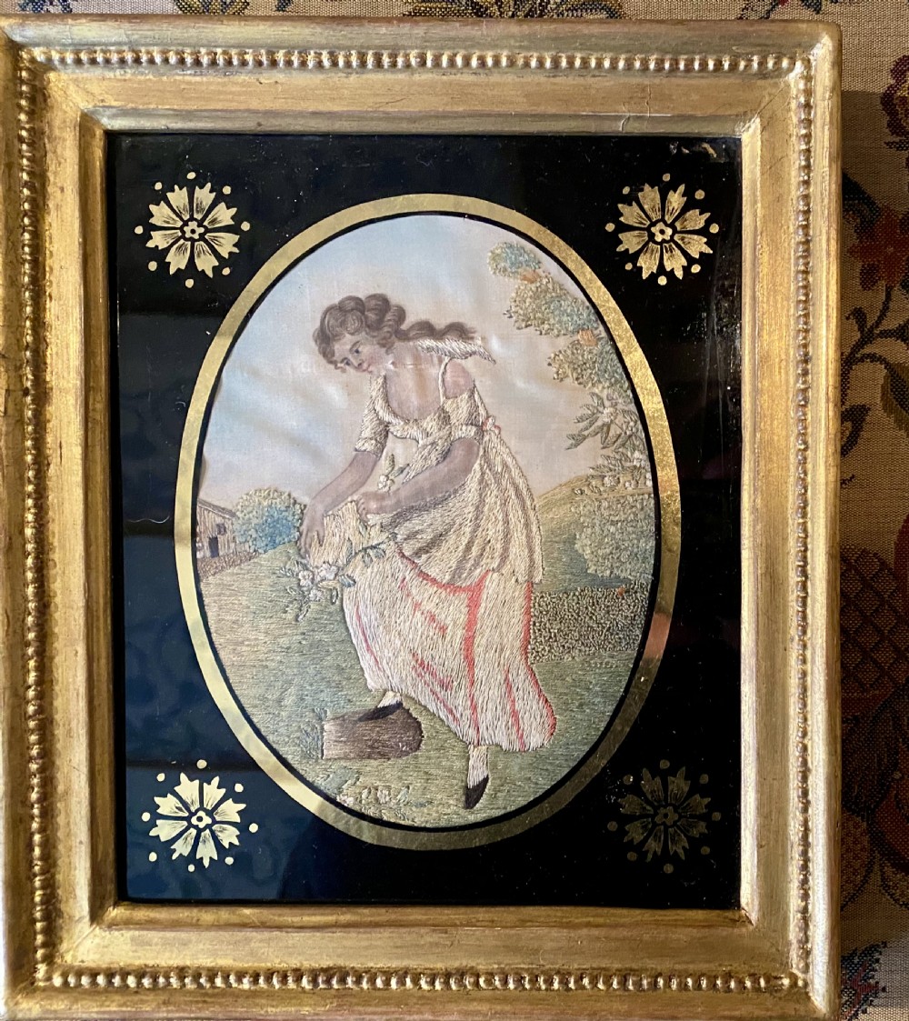 A pair of rectangular gold giltwood framed antique pictures featuring oval silk embroidery of pastoral figures against black glass borders. View VI