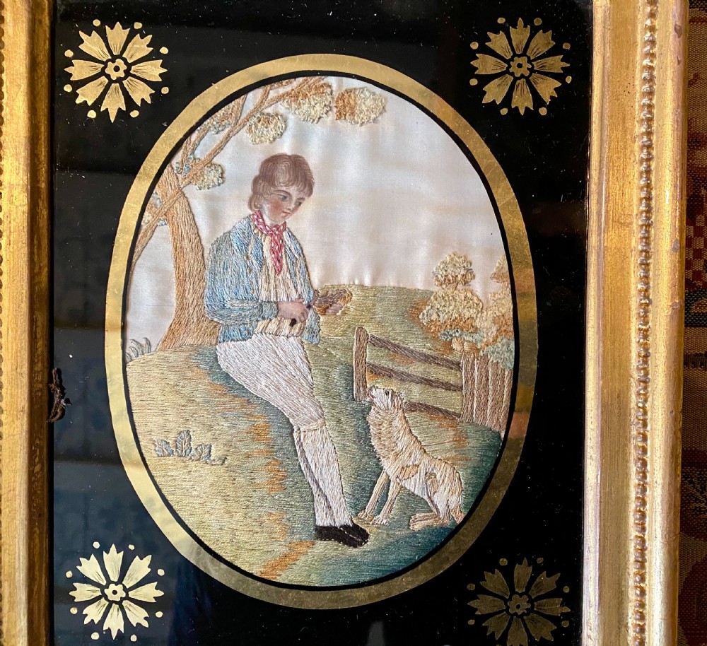 A pair of rectangular gold giltwood framed antique pictures featuring oval silk embroidery of pastoral figures against black glass borders. View VII