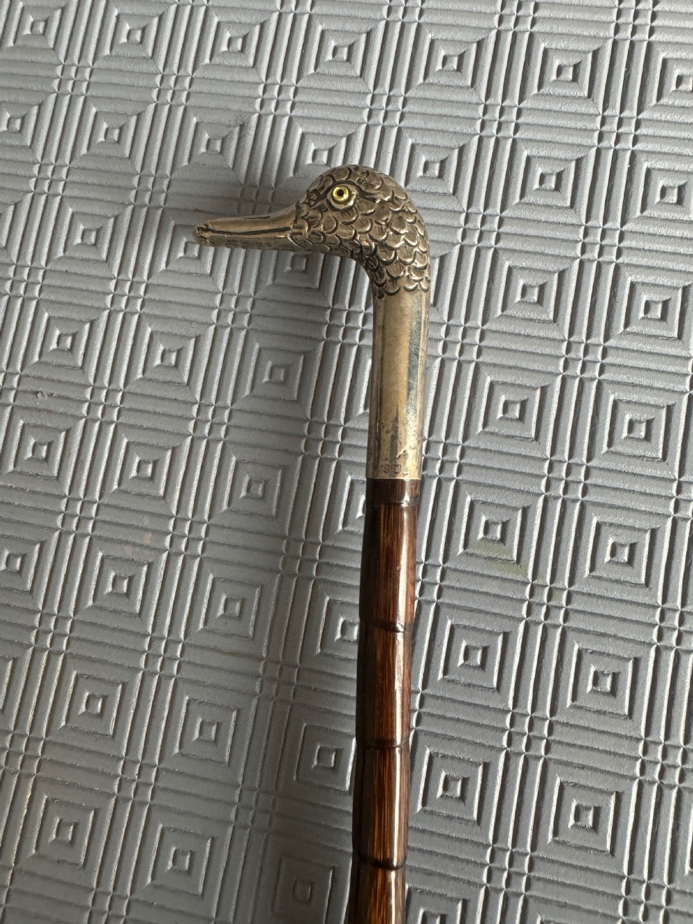 An Edwardian parasol featuring a carved silver duck head handle, a dark wooden shaft, and a folded sage green fabric canopy. View II