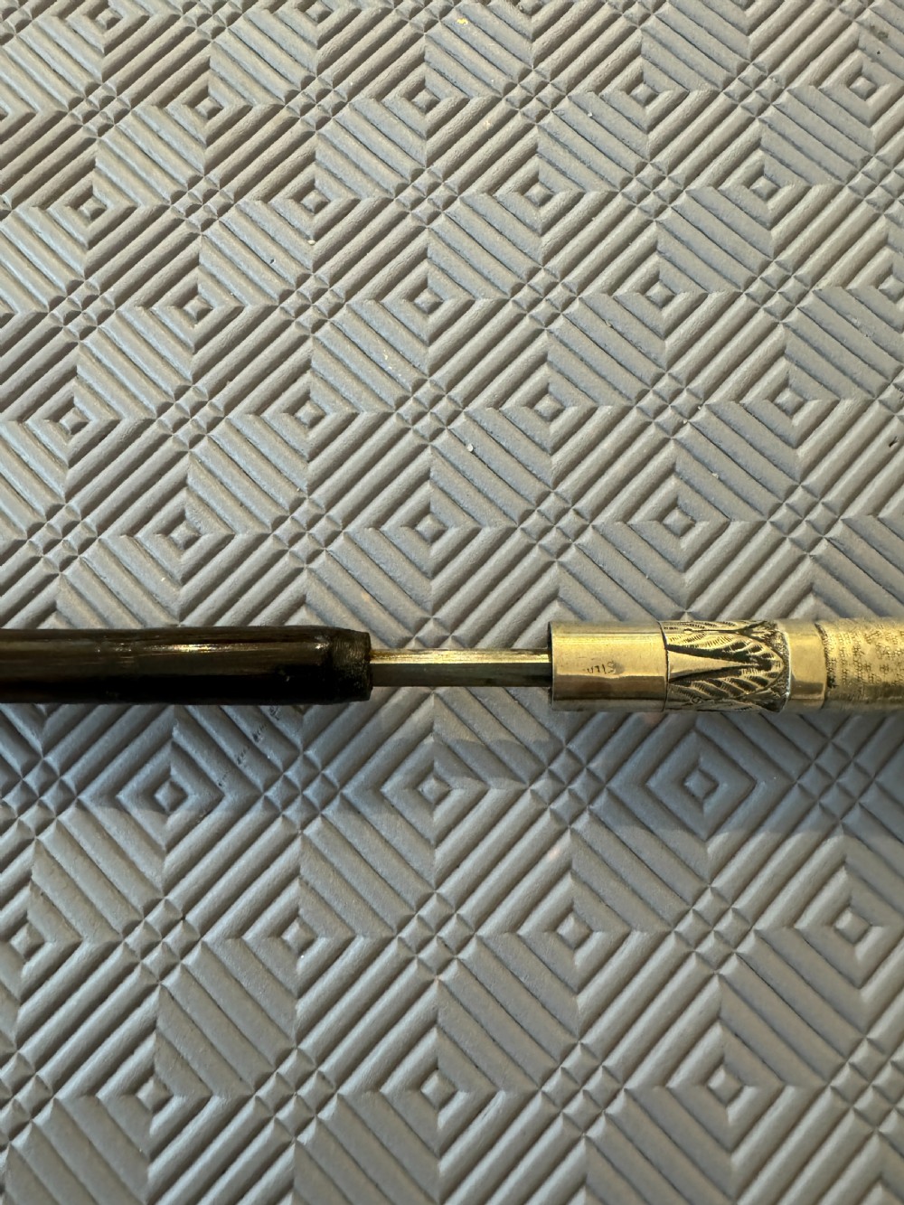 An antique Chinese sword stick featuring a dark wood shaft and an intricately detailed, silver-coloured metal handle decorated with raised figural motifs. View III