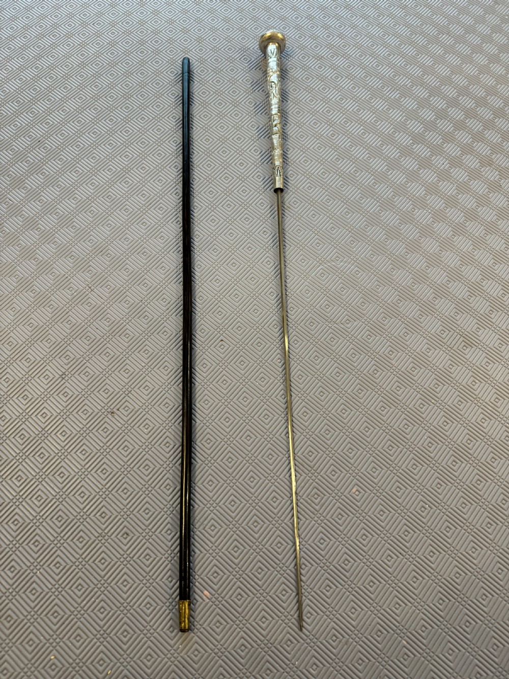 An antique Chinese sword stick featuring a dark wood shaft and an intricately detailed, silver-coloured metal handle decorated with raised figural motifs. View IV