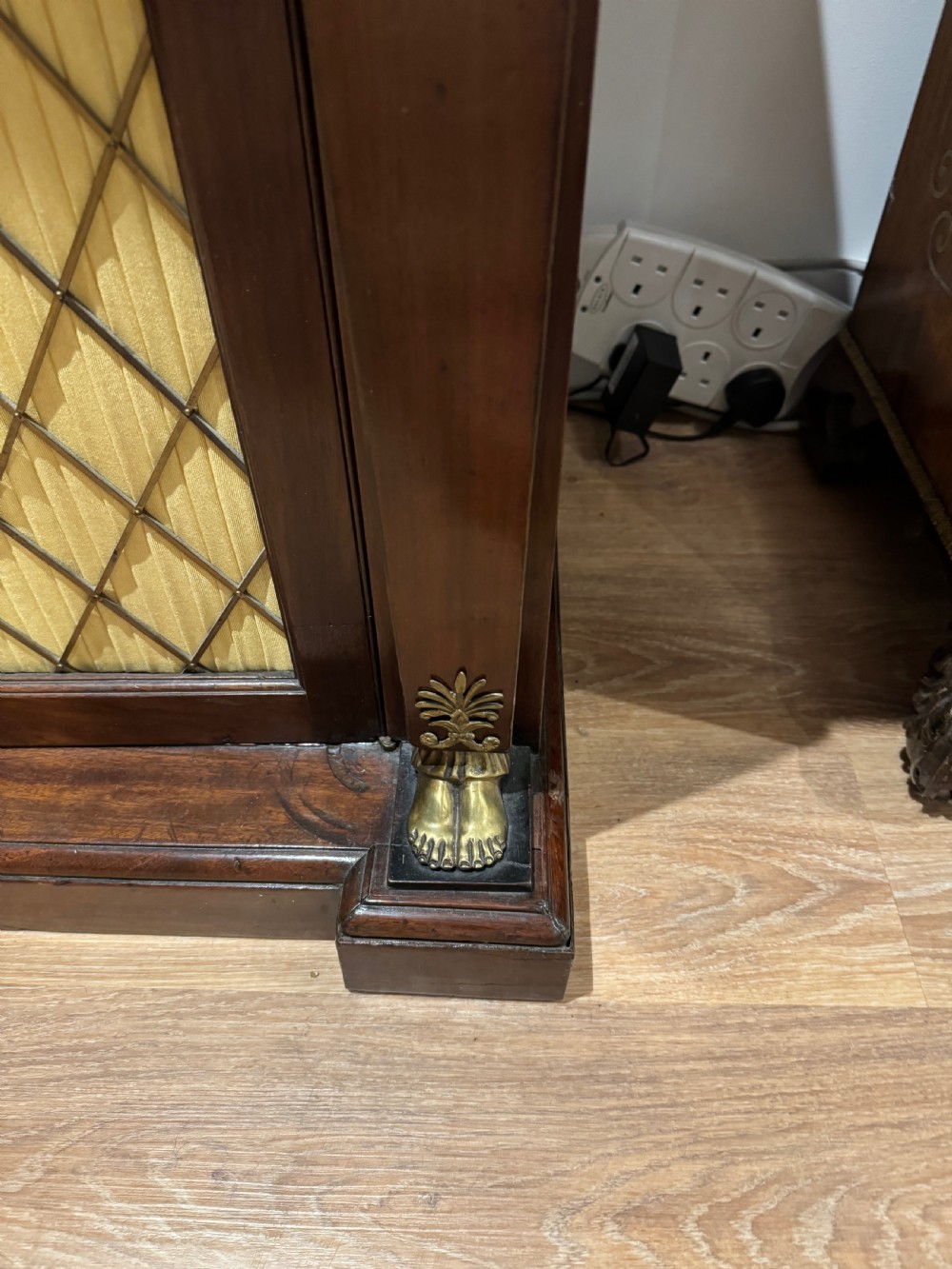 A Regency period dark mahogany side cabinet featuring an original yellow breche marble top, Egyptian revival gilt bronze mounts, and brass wire grille doors with pleated silk backing. View VIII