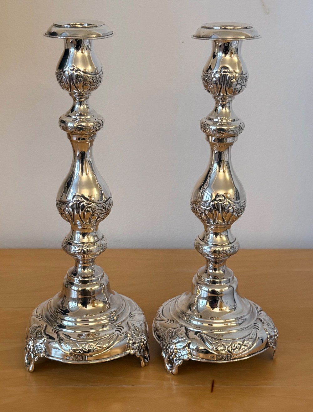 A pair of tall, polished sterling silver Shabbat candlesticks featuring ornate knopped stems and repousse foliate bases. View III