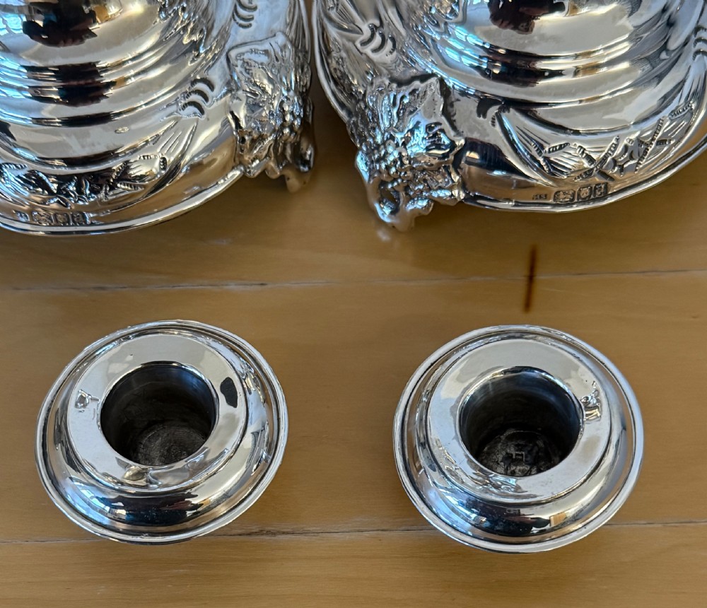 A pair of tall, polished sterling silver Shabbat candlesticks featuring ornate knopped stems and repousse foliate bases. View IV