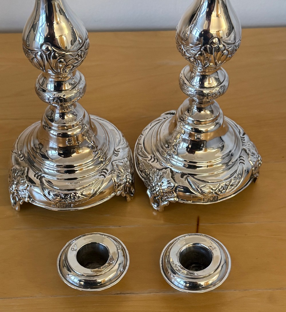 A pair of tall, polished sterling silver Shabbat candlesticks featuring ornate knopped stems and repousse foliate bases. View VI