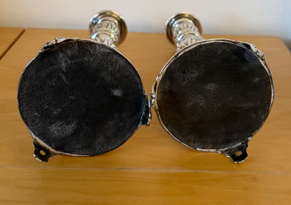 A pair of tall, polished sterling silver Shabbat candlesticks featuring ornate knopped stems and repousse foliate bases. View VII