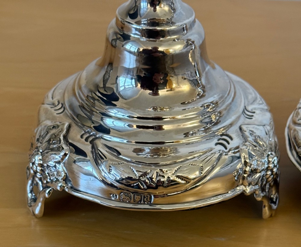 A pair of tall, polished sterling silver Shabbat candlesticks featuring ornate knopped stems and repousse foliate bases. View VIII