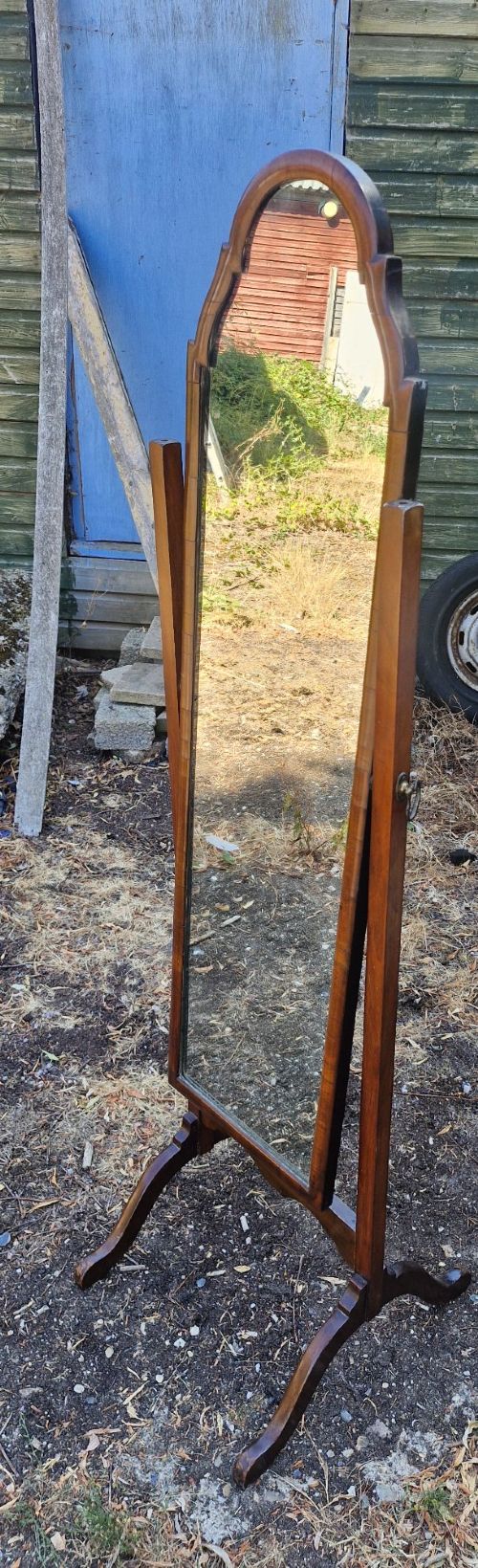 A full-length walnut cheval mirror featuring an arched wooden frame suspended between two vertical uprights on splayed feet. View VI