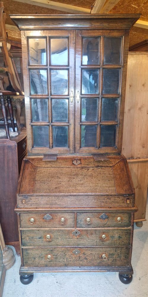 An antique oak bureau bookcase featuring a two-door glazed upper section, a slant-front writing desk, candle slides, and lower drawers raised on bun feet. View II
