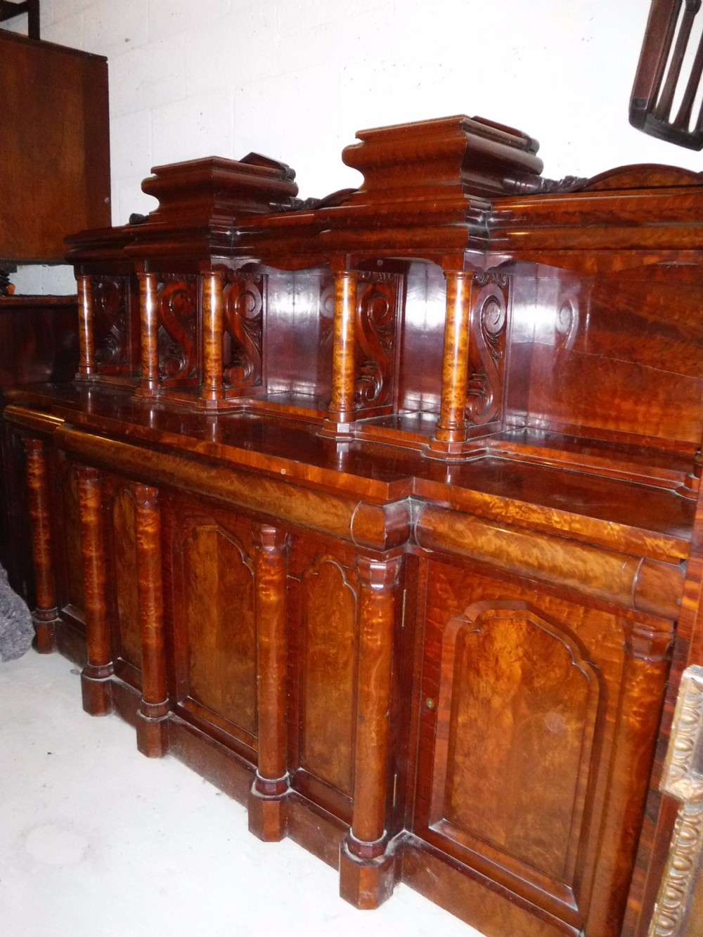 A large Regency mahogany side cabinet featuring turned support columns, panelled cupboard doors, and a tier of raised shelves. View II