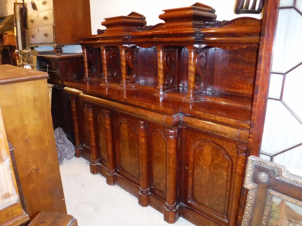 A large Regency mahogany side cabinet featuring turned support columns, panelled cupboard doors, and a tier of raised shelves. View III