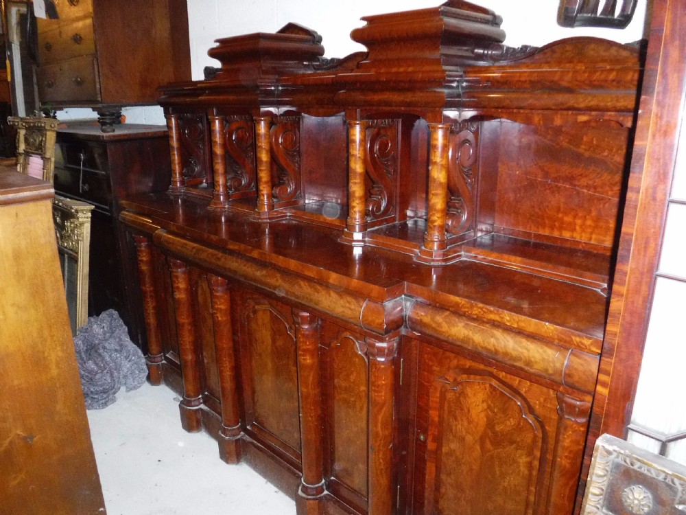 A large Regency mahogany side cabinet featuring turned support columns, panelled cupboard doors, and a tier of raised shelves. View IV