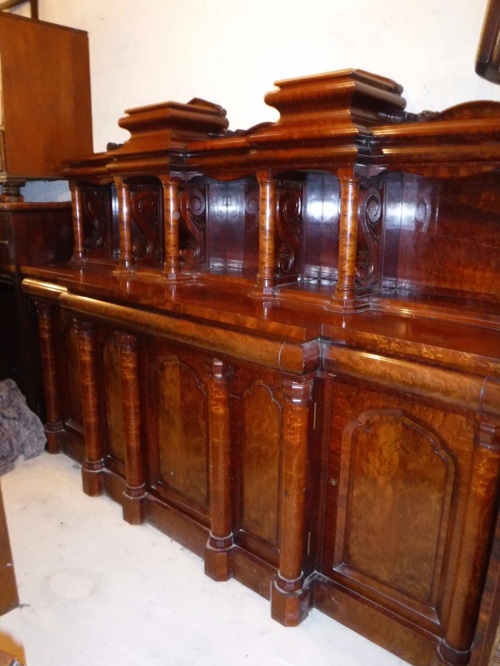 A large Regency mahogany side cabinet featuring turned support columns, panelled cupboard doors, and a tier of raised shelves. View V