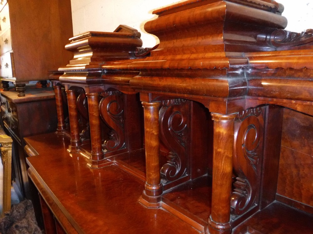 A large Regency mahogany side cabinet featuring turned support columns, panelled cupboard doors, and a tier of raised shelves. View VI