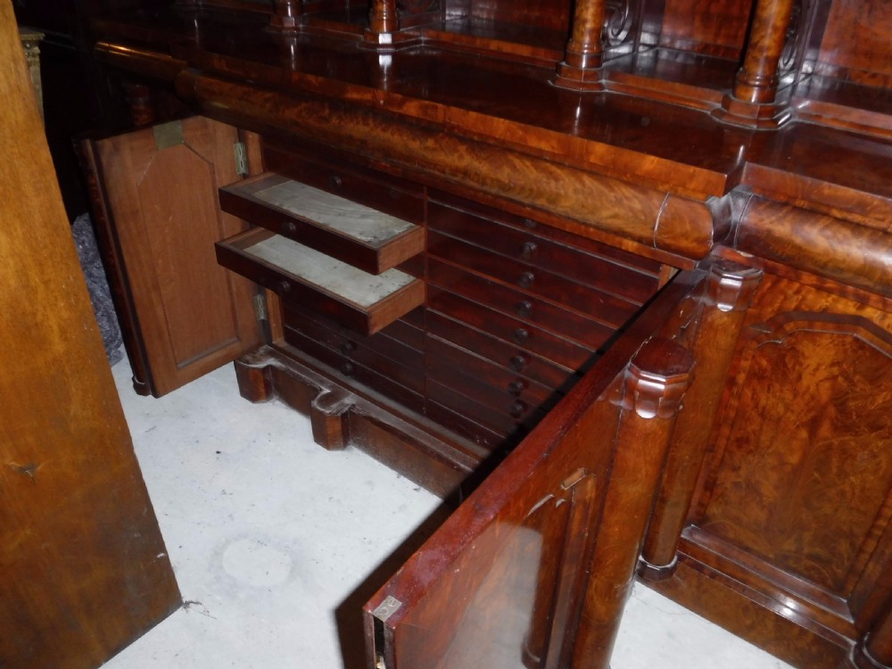 A large Regency mahogany side cabinet featuring turned support columns, panelled cupboard doors, and a tier of raised shelves. View VIII