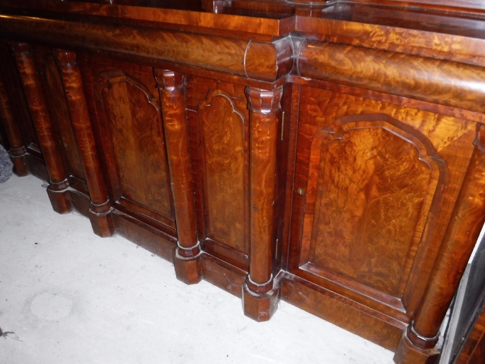 A large Regency mahogany side cabinet featuring turned support columns, panelled cupboard doors, and a tier of raised shelves. View X