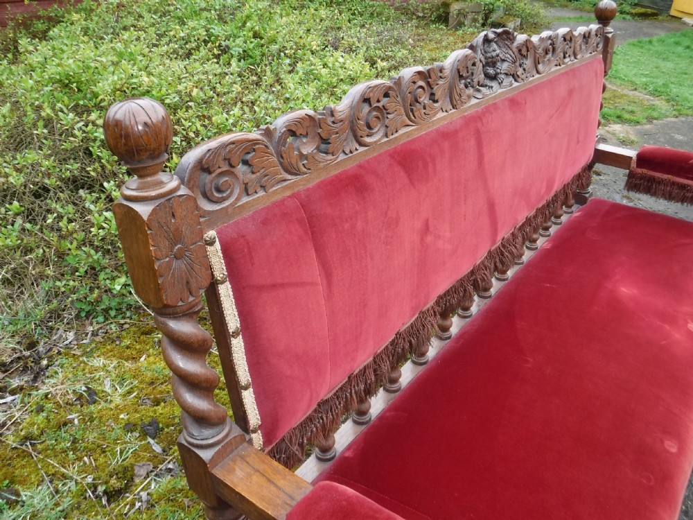 A late nineteenth-century carved oak hall bench featuring red velvet upholstery with fringe trim and barley twist legs. View V
