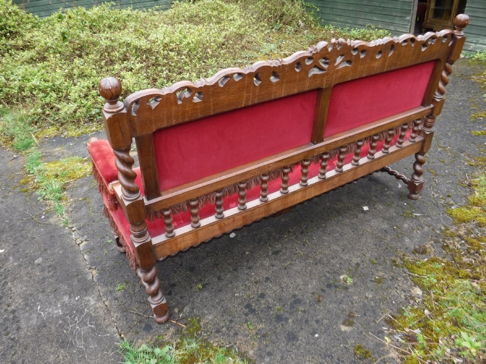 A late nineteenth-century carved oak hall bench featuring red velvet upholstery with fringe trim and barley twist legs. View VI