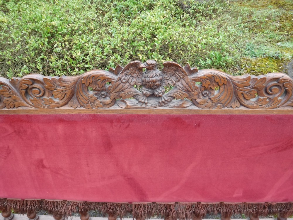 A late nineteenth-century carved oak hall bench featuring red velvet upholstery with fringe trim and barley twist legs. View VII