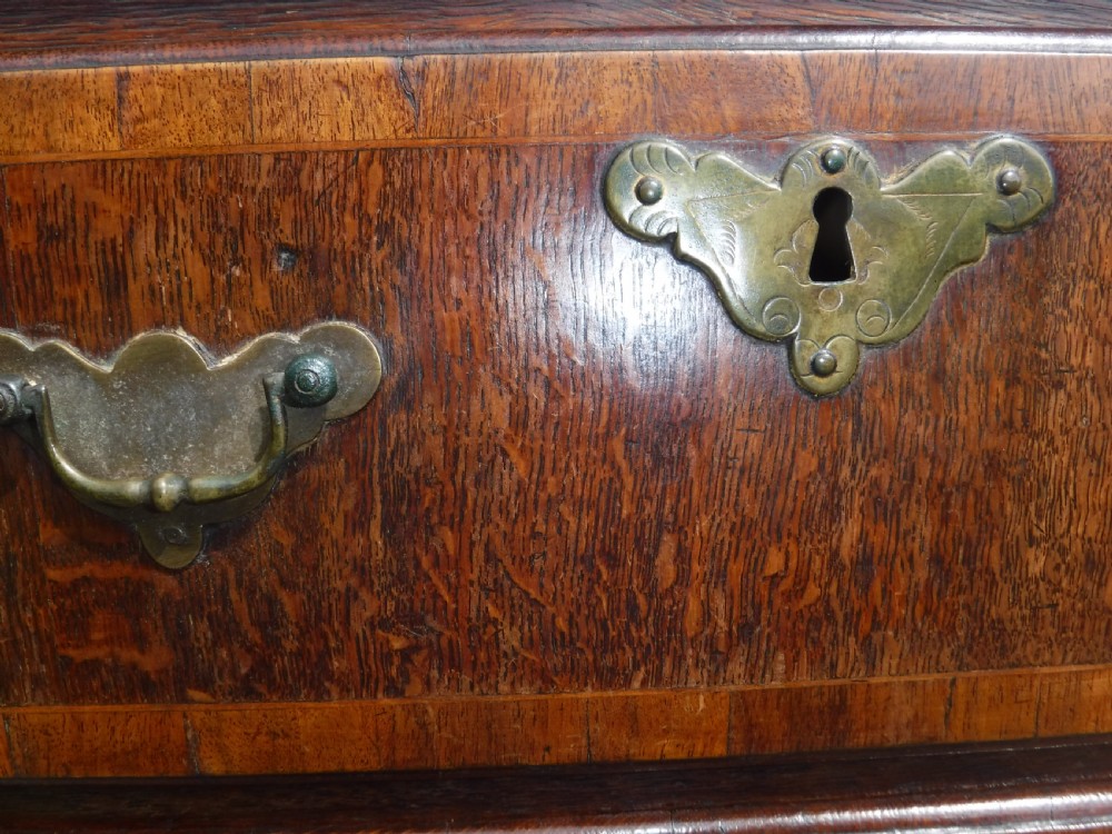 An early eighteenth-century oak chest on stand featuring crossbanded drawer fronts, brass drop handles, keyhole escutcheons, a shaped apron, and cabriole legs with pad feet. View VIII