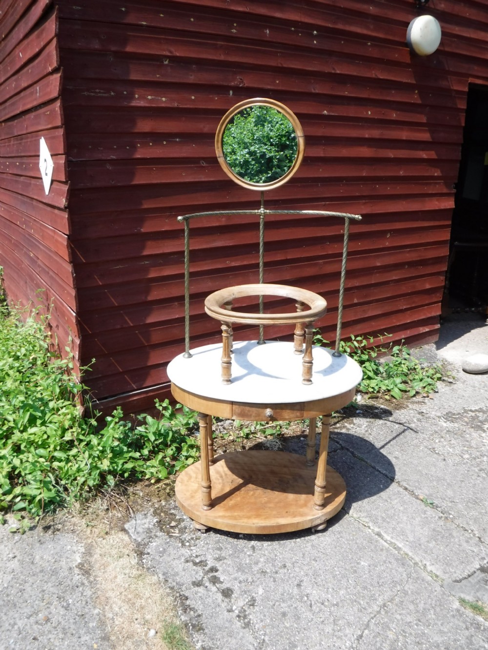 Late Victorian circular satin birch washstand featuring a white marble top, turned legs, lower tier, basin support ring, and attached brass superstructure with a round swivel mirror.