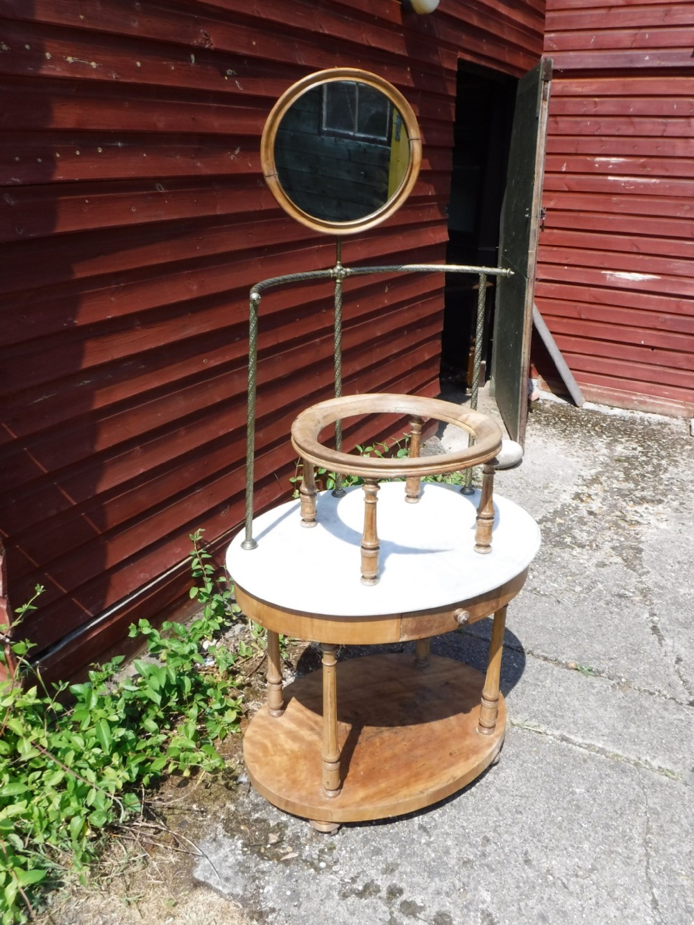 Late Victorian circular satin birch washstand featuring a white marble top, turned legs, lower tier, basin support ring, and attached brass superstructure with a round swivel mirror. View II