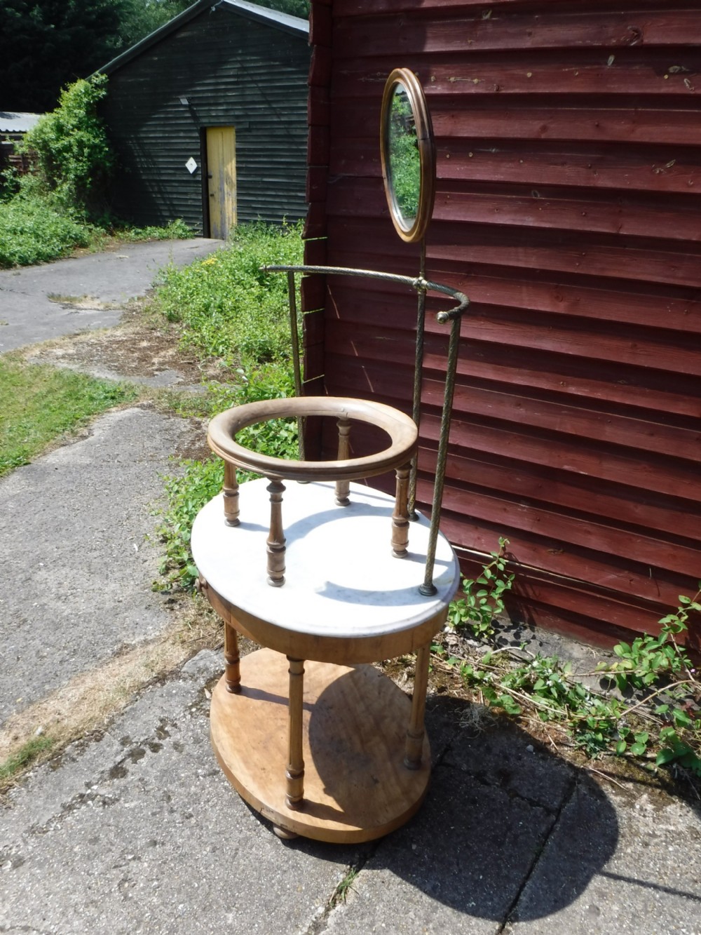 Late Victorian circular satin birch washstand featuring a white marble top, turned legs, lower tier, basin support ring, and attached brass superstructure with a round swivel mirror. View III