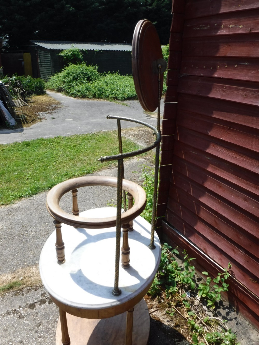 Late Victorian circular satin birch washstand featuring a white marble top, turned legs, lower tier, basin support ring, and attached brass superstructure with a round swivel mirror. View IV