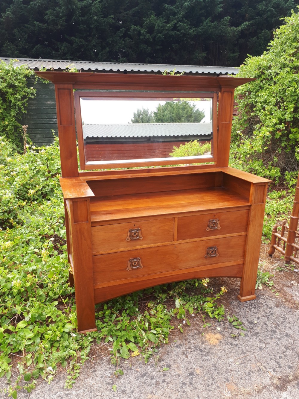 A late nineteenth-century Arts and Crafts wooden dressing chest featuring an integrated mirror, upper mantle shelf, two short drawers, one long drawer, and copper backplate handles. View II