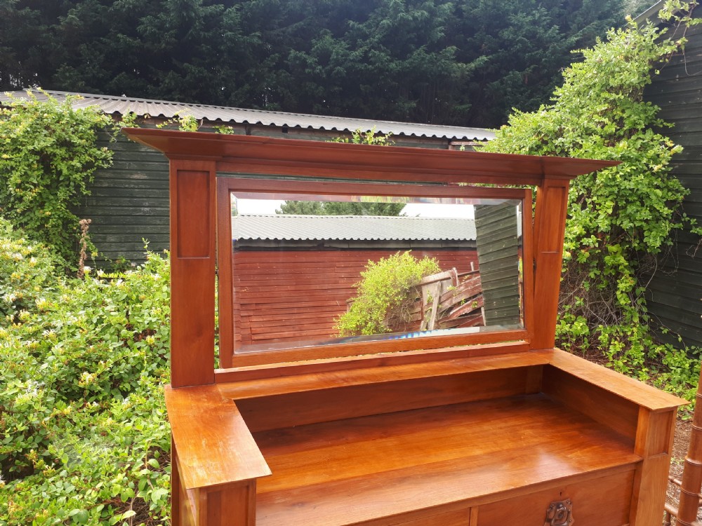 A late nineteenth-century Arts and Crafts wooden dressing chest featuring an integrated mirror, upper mantle shelf, two short drawers, one long drawer, and copper backplate handles. View III