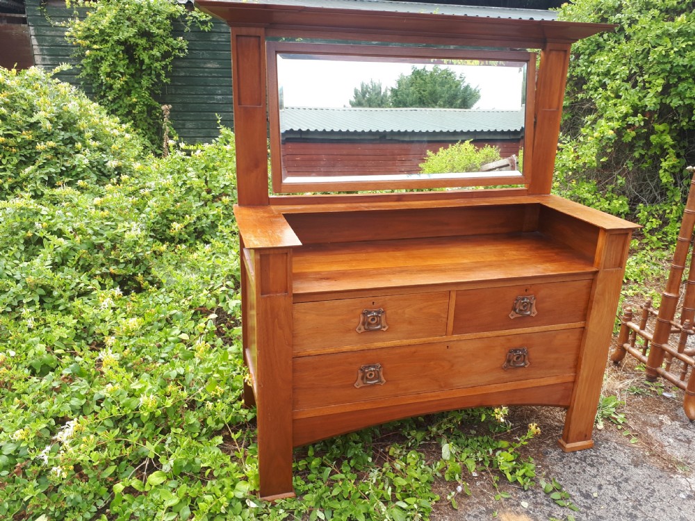 A late nineteenth-century Arts and Crafts wooden dressing chest featuring an integrated mirror, upper mantle shelf, two short drawers, one long drawer, and copper backplate handles. View IX