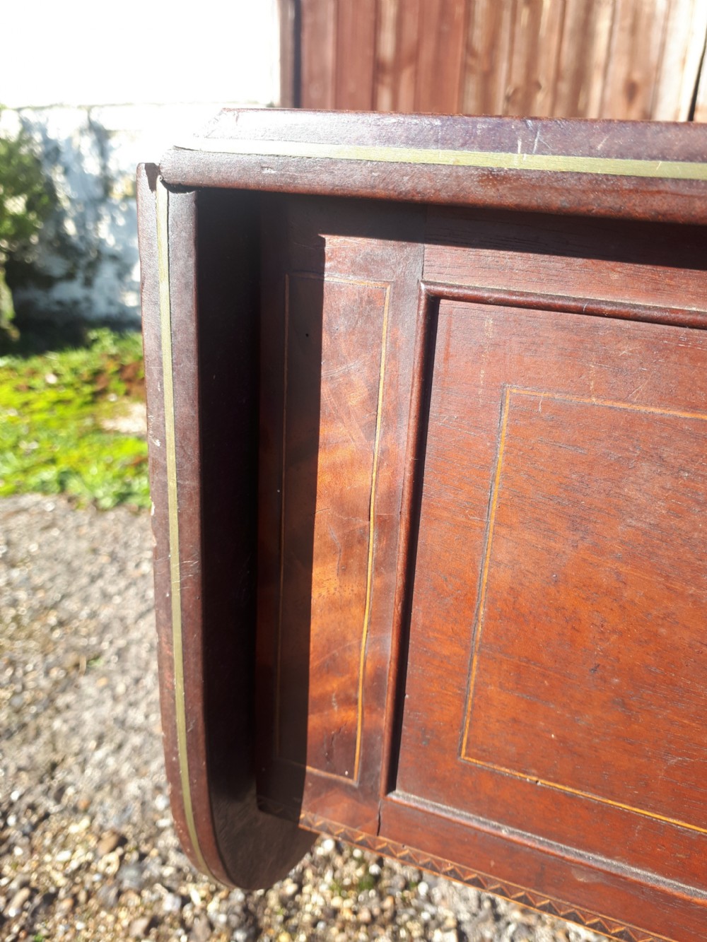 A Regency mahogany sofa table with brass line inlay, drop leaves, a single drawer, and splayed legs resting on brass castors. View VI