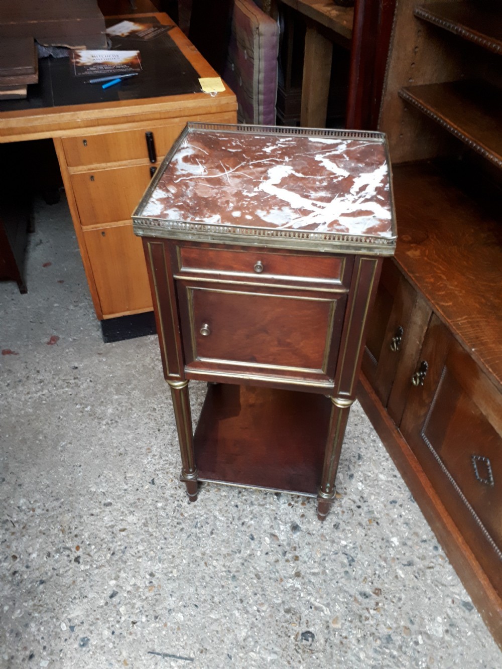 A 19th-century mahogany bedside cabinet featuring a red veined marble top with a brass gallery, a single drawer, a cupboard door, brass inlay trim, and fluted legs with an open lower shelf.
