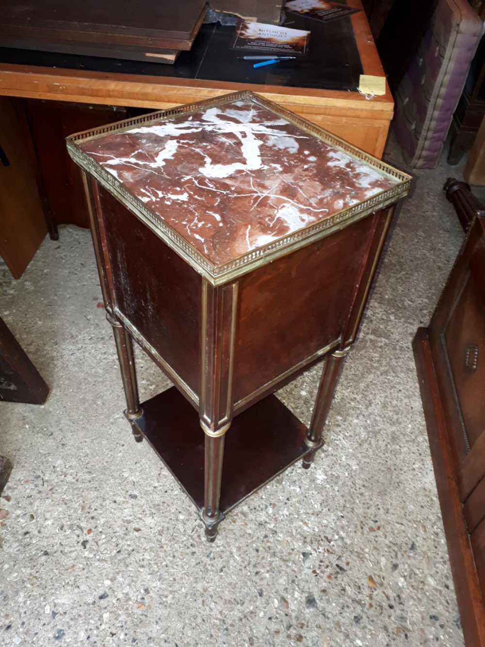 A 19th-century mahogany bedside cabinet featuring a red veined marble top with a brass gallery, a single drawer, a cupboard door, brass inlay trim, and fluted legs with an open lower shelf. View V