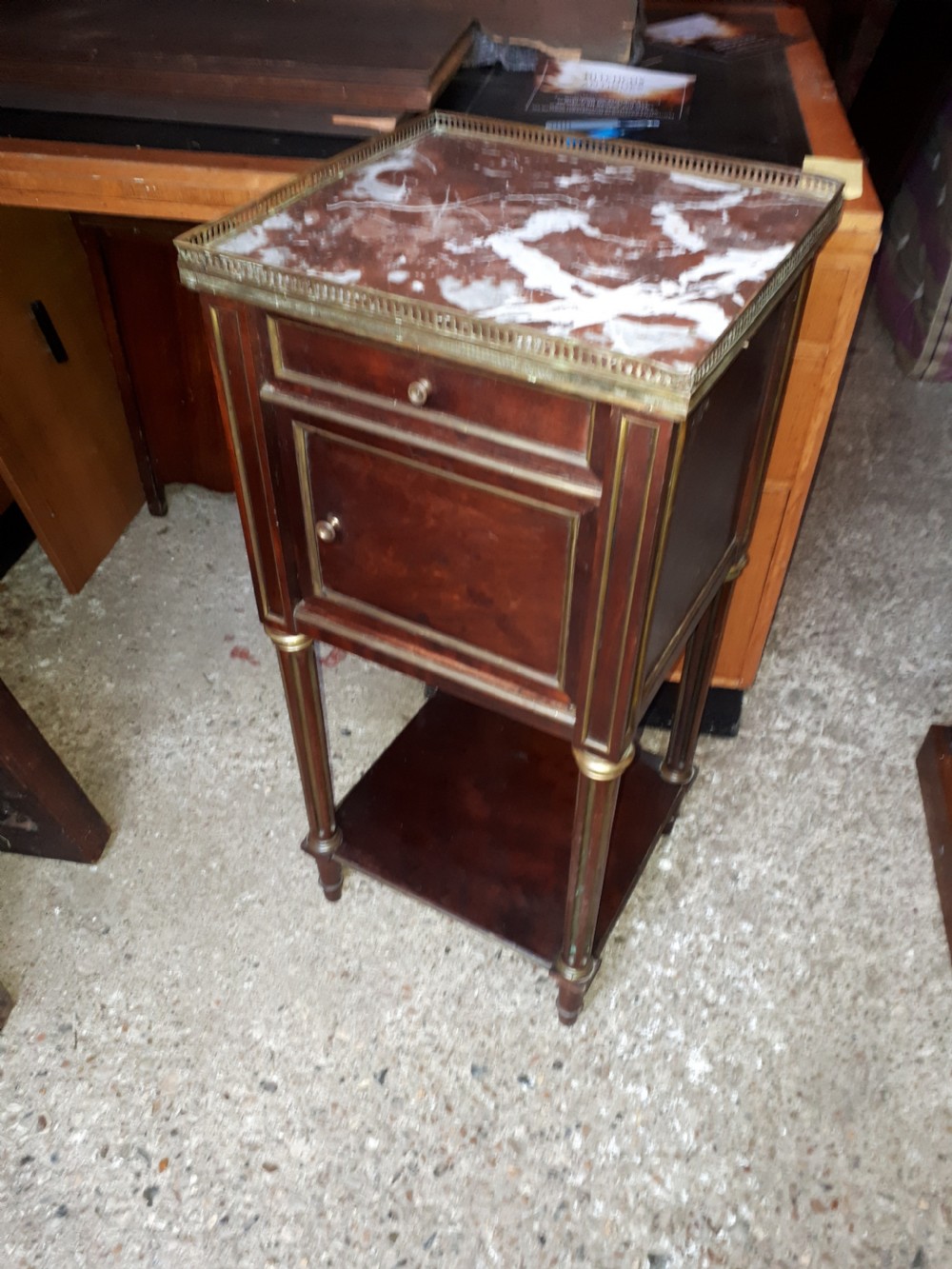 A 19th-century mahogany bedside cabinet featuring a red veined marble top with a brass gallery, a single drawer, a cupboard door, brass inlay trim, and fluted legs with an open lower shelf. View VII