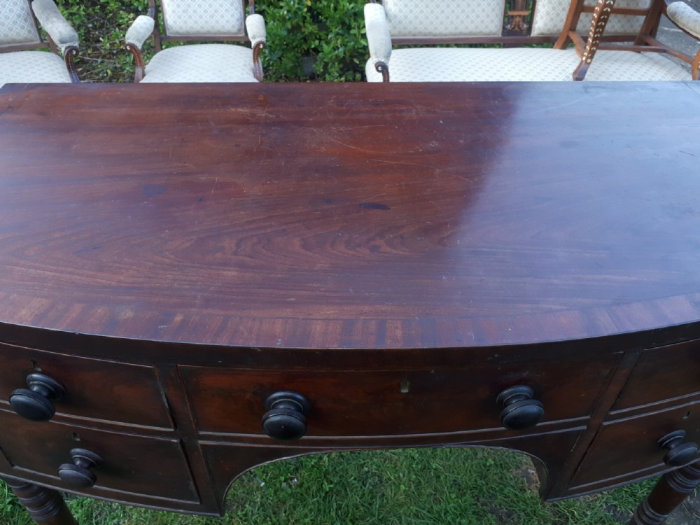 A nineteenth-century Regency mahogany bow-fronted sideboard featuring five drawers with turned wooden knobs and four turned legs. View VII