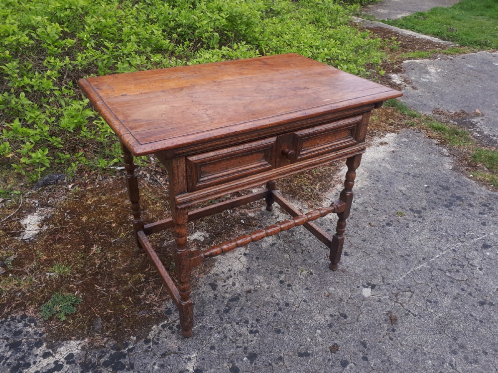 An antique oak side table featuring a single moulded drawer, turned legs, and lower stretchers.