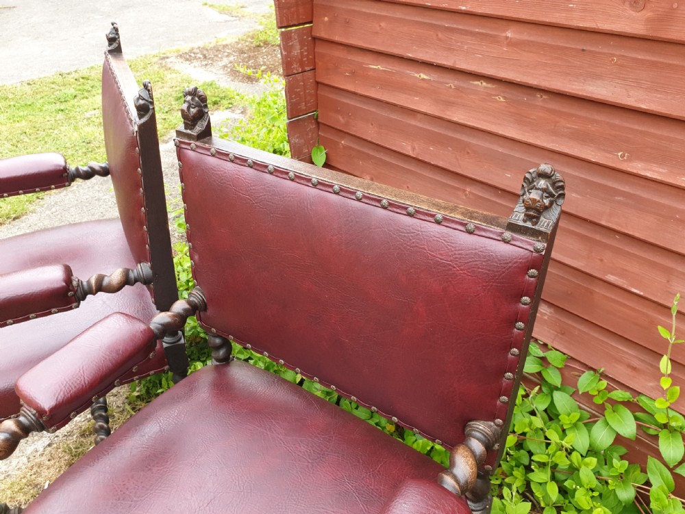 A pair of late 19th-century dark oak armchairs featuring barley twist legs and stretchers, carved finials, and burgundy leather upholstery secured with decorative brass studs. View III