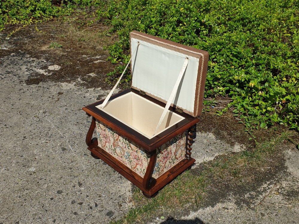 An early Victorian rosewood box seat stool with a brown padded cushion seat, floral upholstered fabric side panels, and shaped wooden supports. View II
