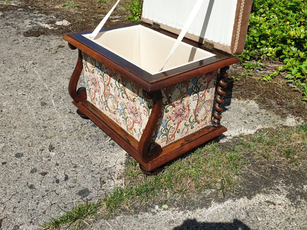An early Victorian rosewood box seat stool with a brown padded cushion seat, floral upholstered fabric side panels, and shaped wooden supports. View VI