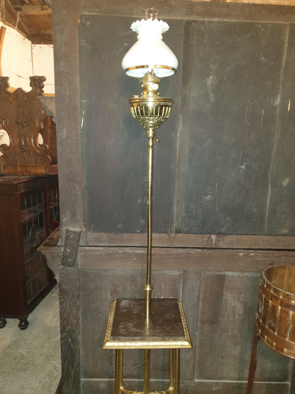 A Victorian brass floor lamp featuring an integrated square tier, splayed legs, and a white frilled milk glass shade. View II