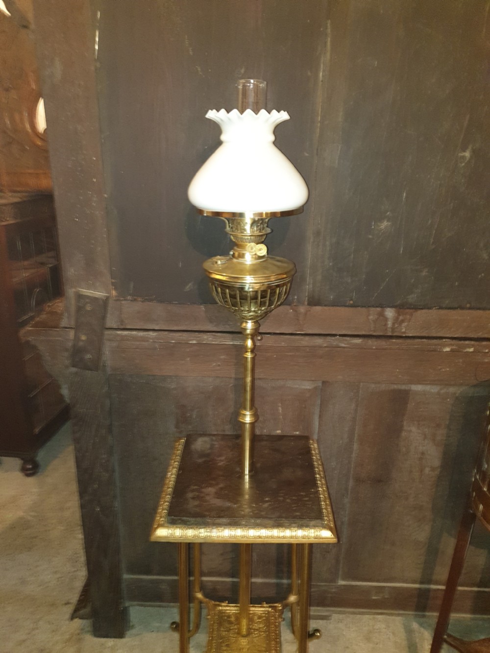 A Victorian brass floor lamp featuring an integrated square tier, splayed legs, and a white frilled milk glass shade. View III