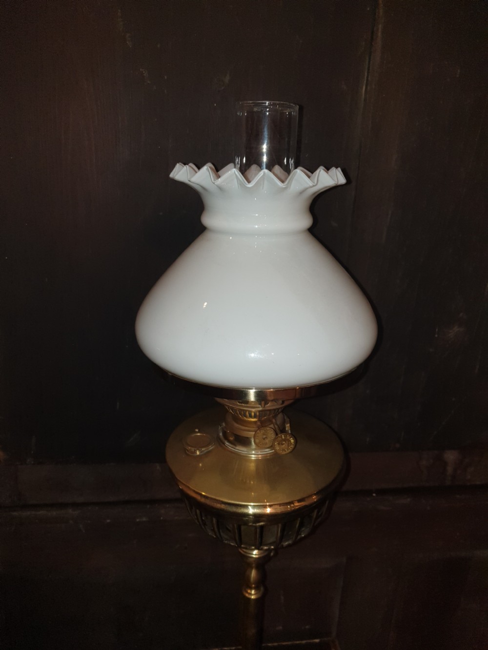 A Victorian brass floor lamp featuring an integrated square tier, splayed legs, and a white frilled milk glass shade. View VI