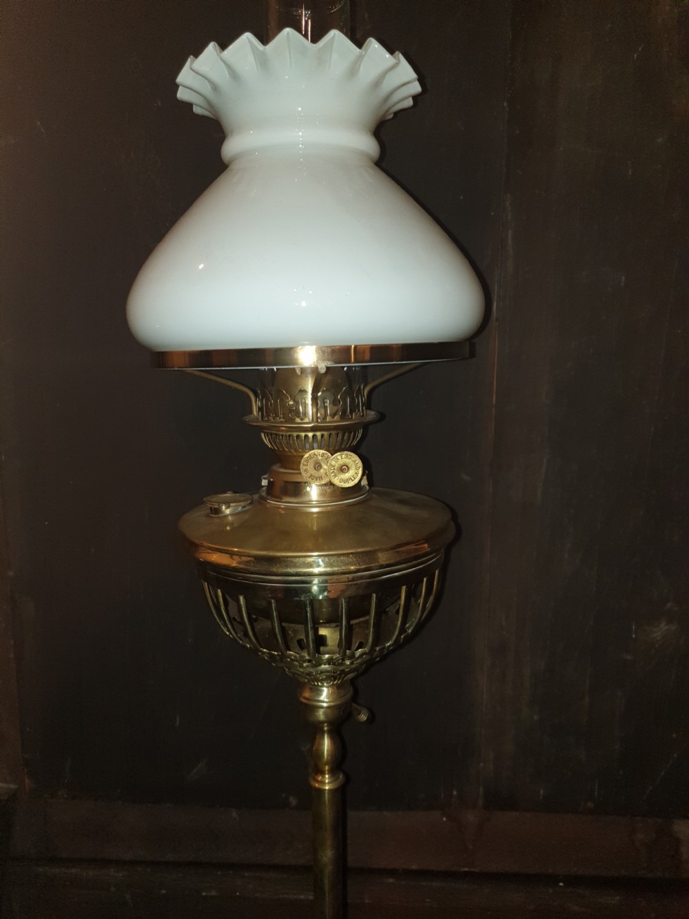 A Victorian brass floor lamp featuring an integrated square tier, splayed legs, and a white frilled milk glass shade. View VII