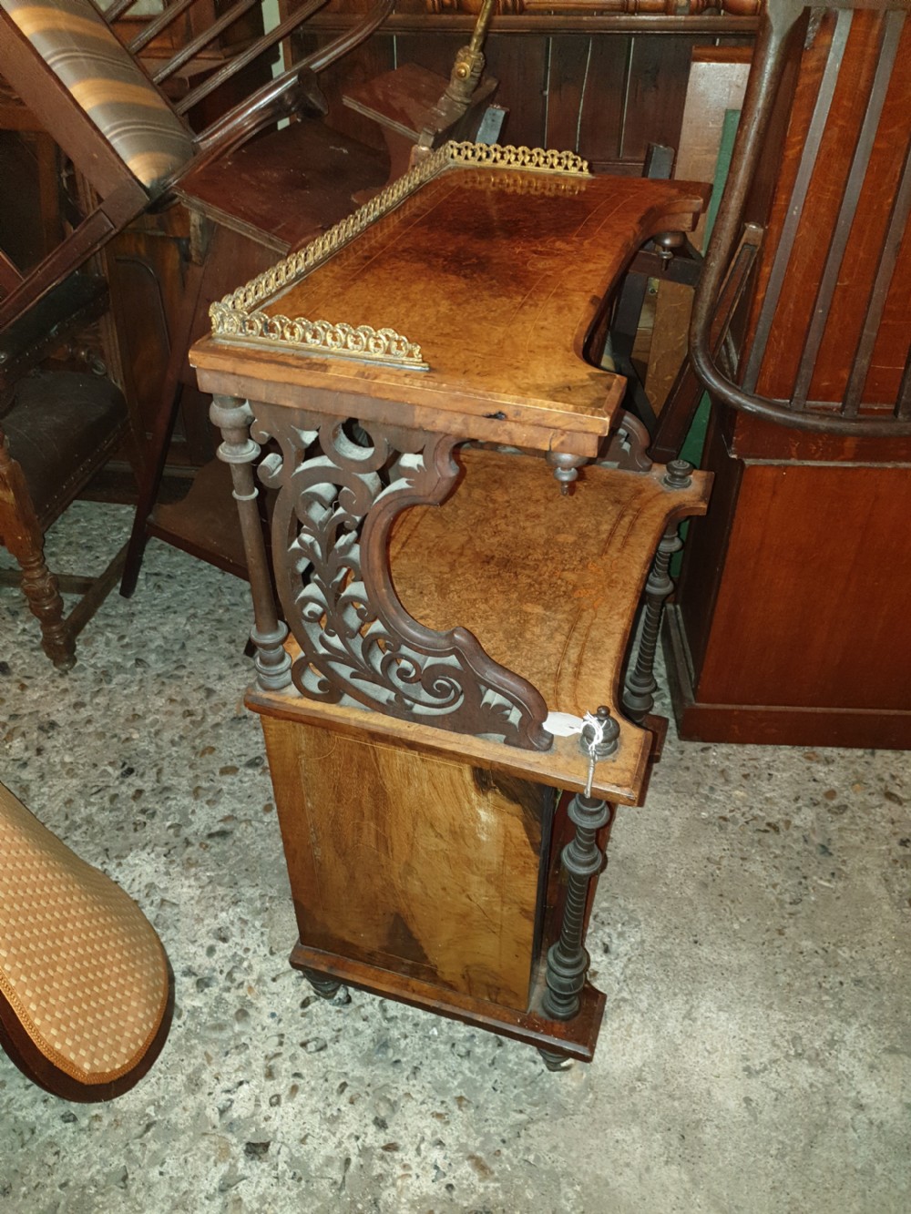 A Victorian burr walnut music cabinet featuring an upper shelf with a pierced brass gallery rail, turned upright columns, marquetry inlay, and a glass door opening to labelled shelves. View V