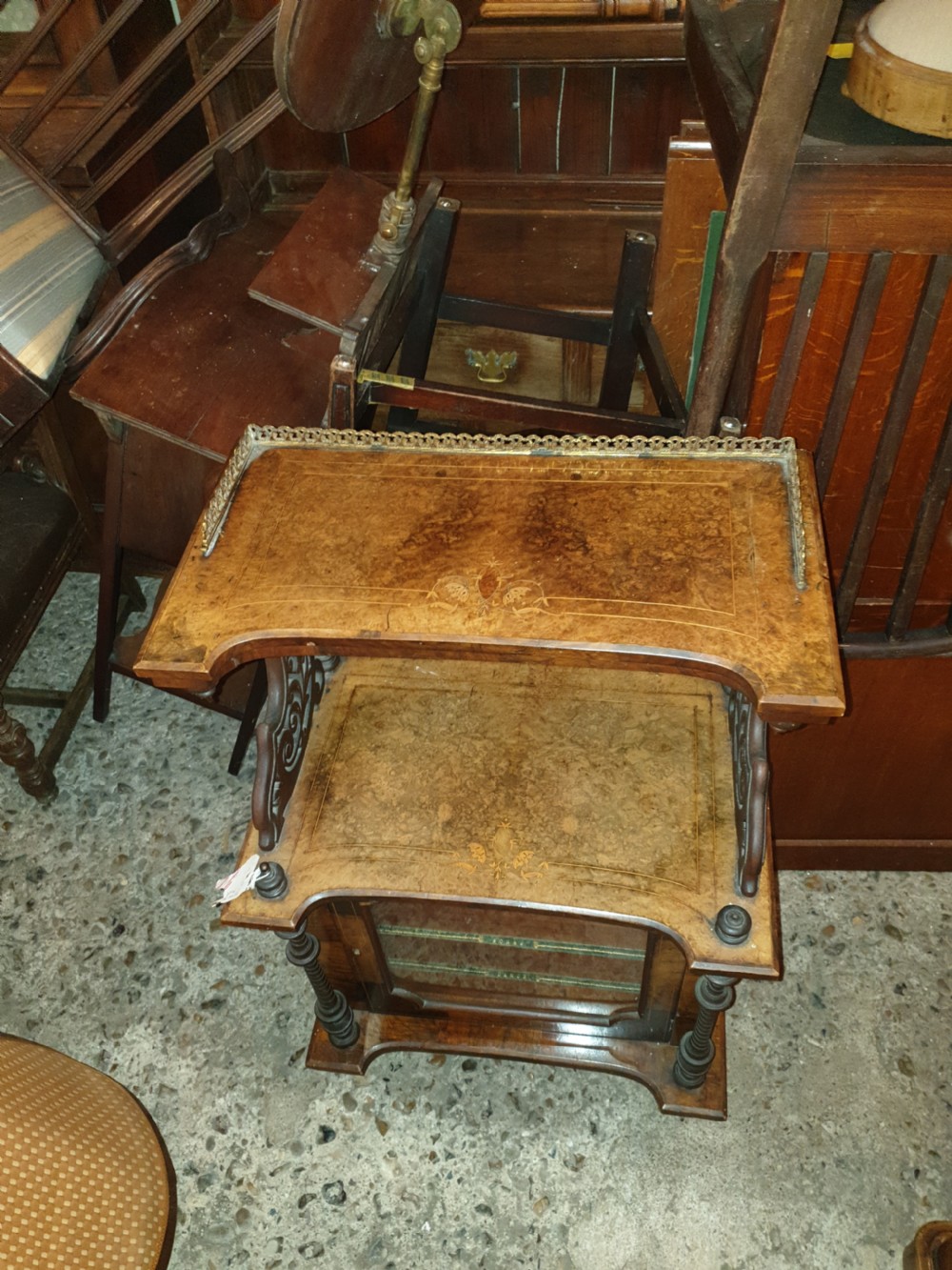 A Victorian burr walnut music cabinet featuring an upper shelf with a pierced brass gallery rail, turned upright columns, marquetry inlay, and a glass door opening to labelled shelves. View VI